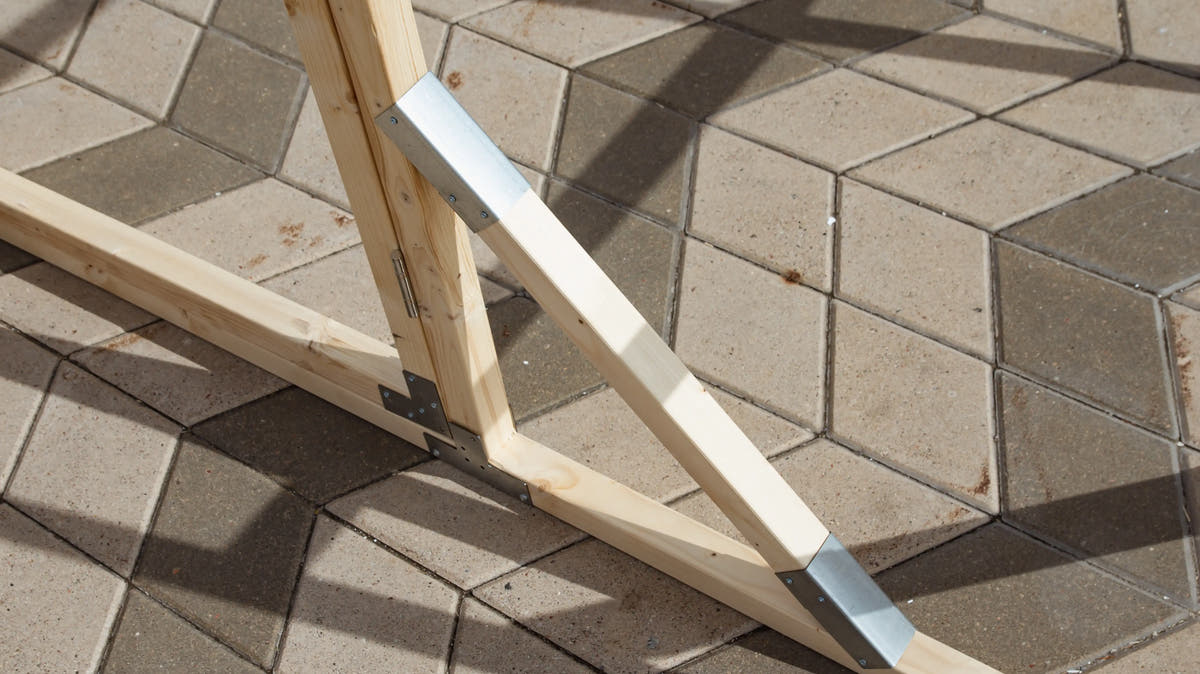 Corner of a NORDIC pine base frame with galvanised brackets, set on paving slabs