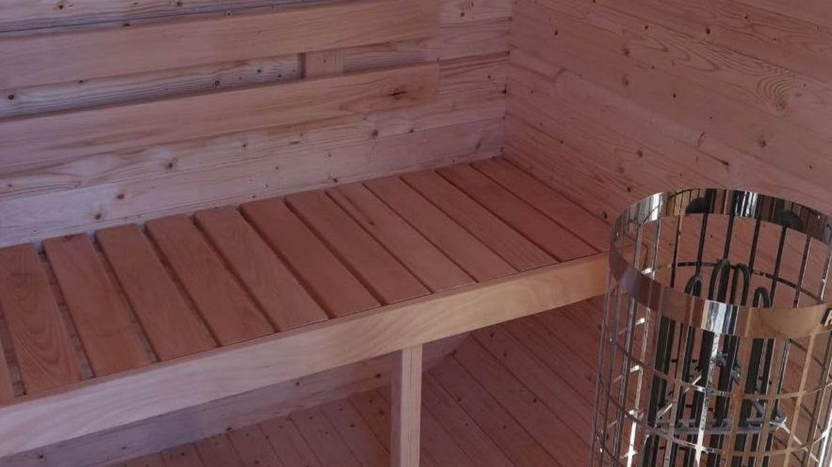 Harvia electric pillar heater with stones beside the bench inside The Cabin Three sauna