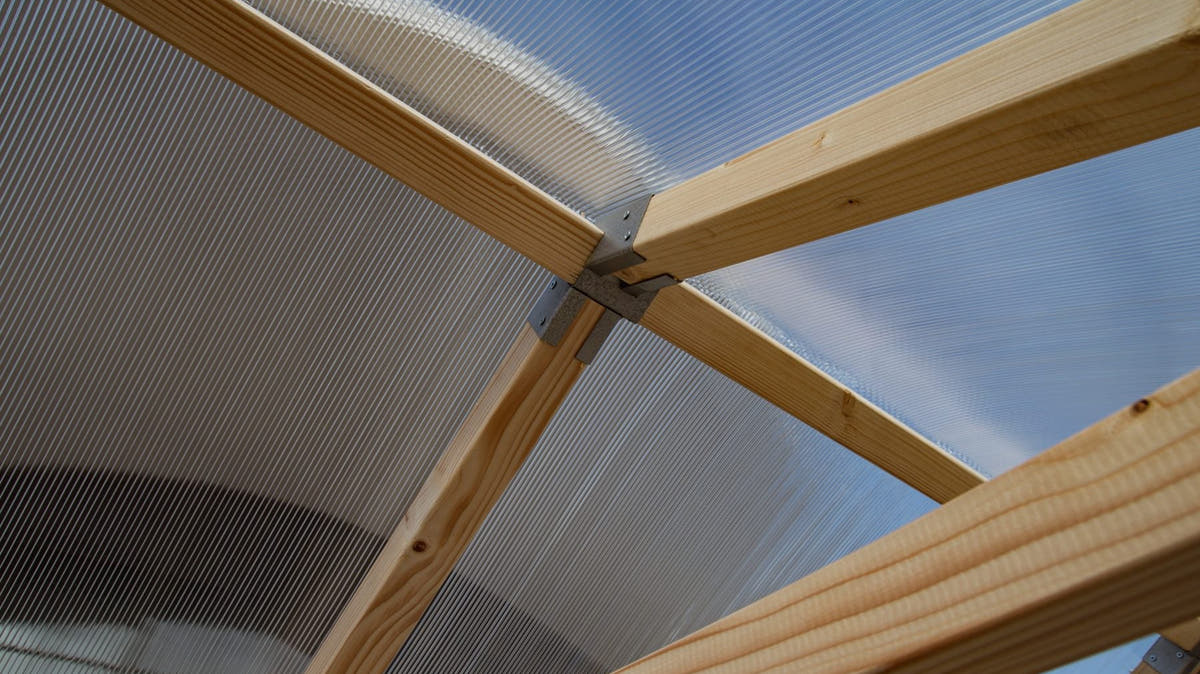 Twin-wall polycarbonate roof and pine rafters of a NORDIC greenhouse, seen from below