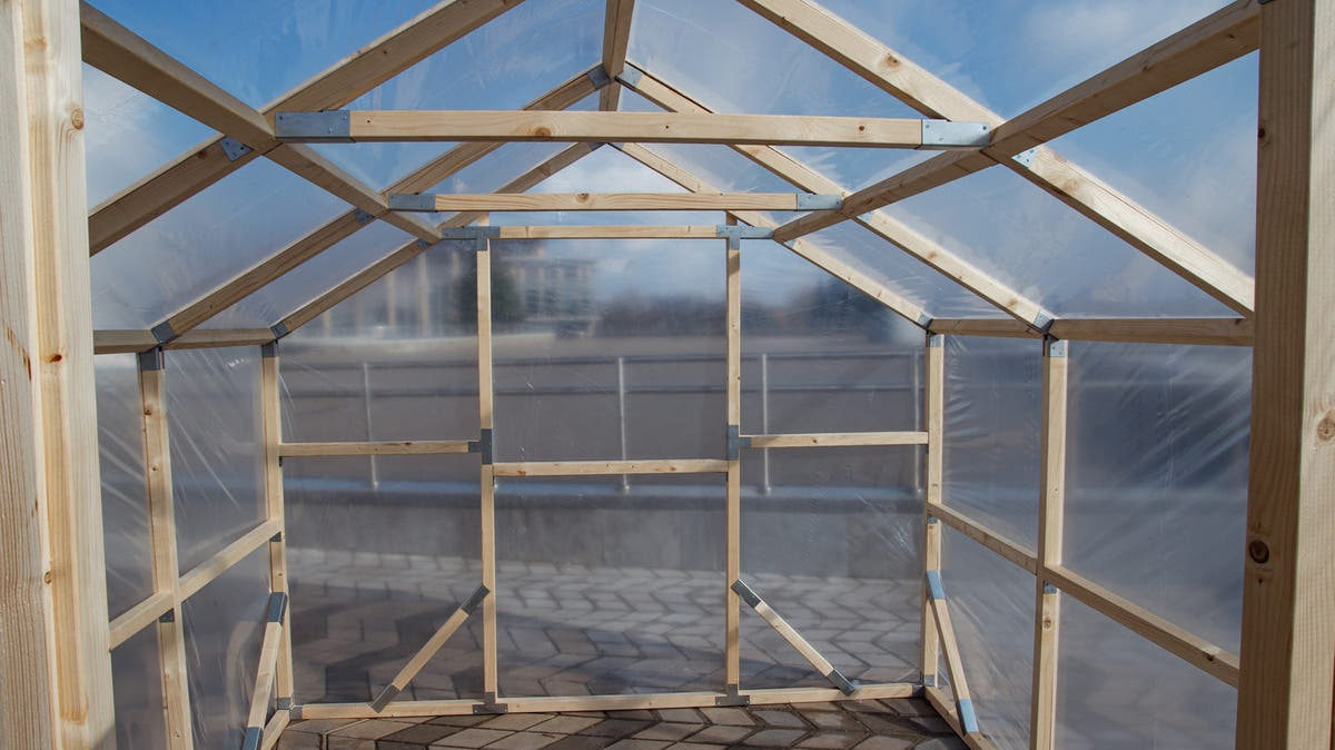 Inside an empty NORDIC greenhouse: pine frame, braces and walk-in headroom, ready for staging