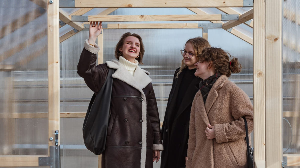 Three adults standing inside a NORDIC wooden greenhouse, showing the walk-in headroom