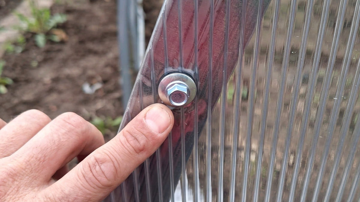 Twin-wall polycarbonate sheet fixed with a screw and washer on a SteelRoot greenhouse arch