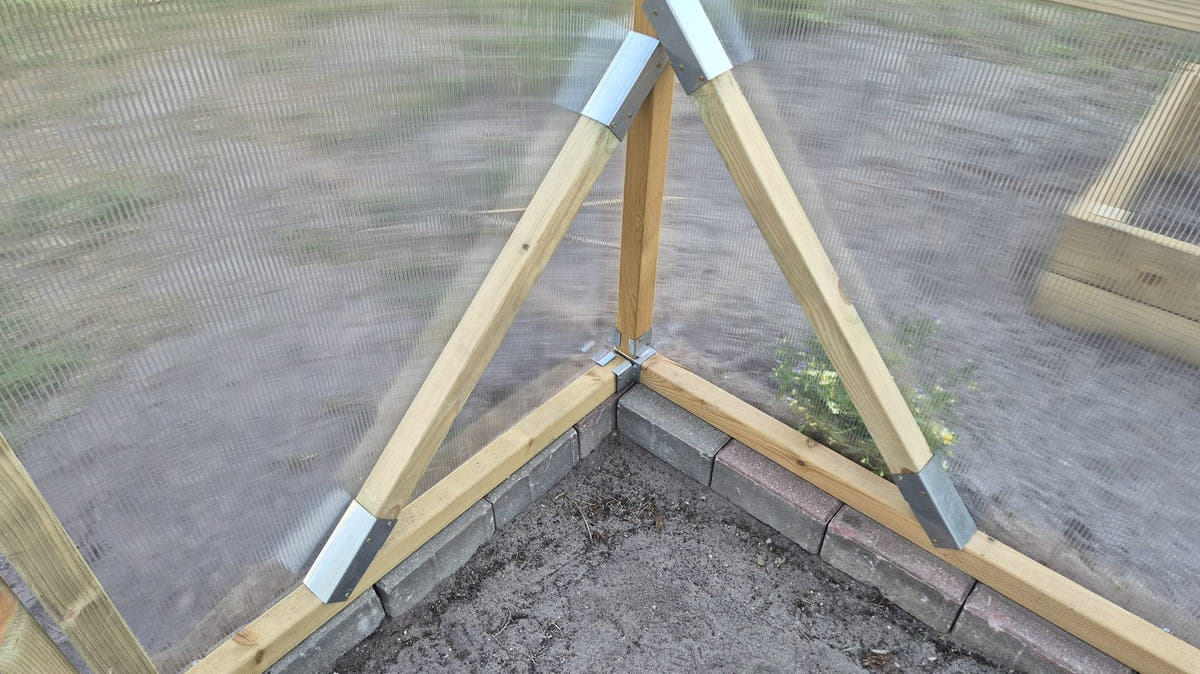 Diagonal corner braces and galvanised brackets at the base of a NORDIC wooden greenhouse