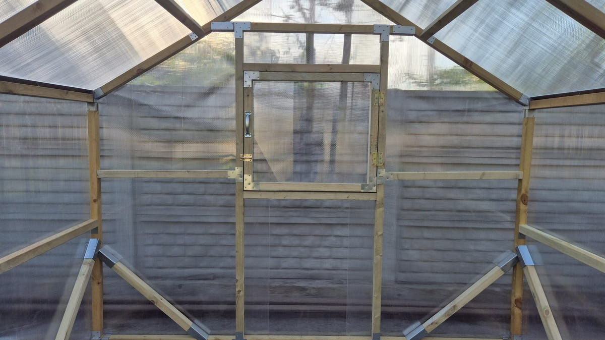 Gable end of a NORDIC greenhouse from inside, with the opening window above the braces