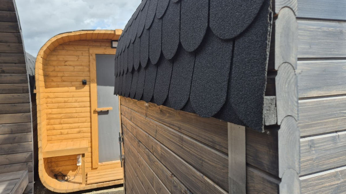 Outdoor saunas with shingle roofs fitted, waiting in the yard before dispatch