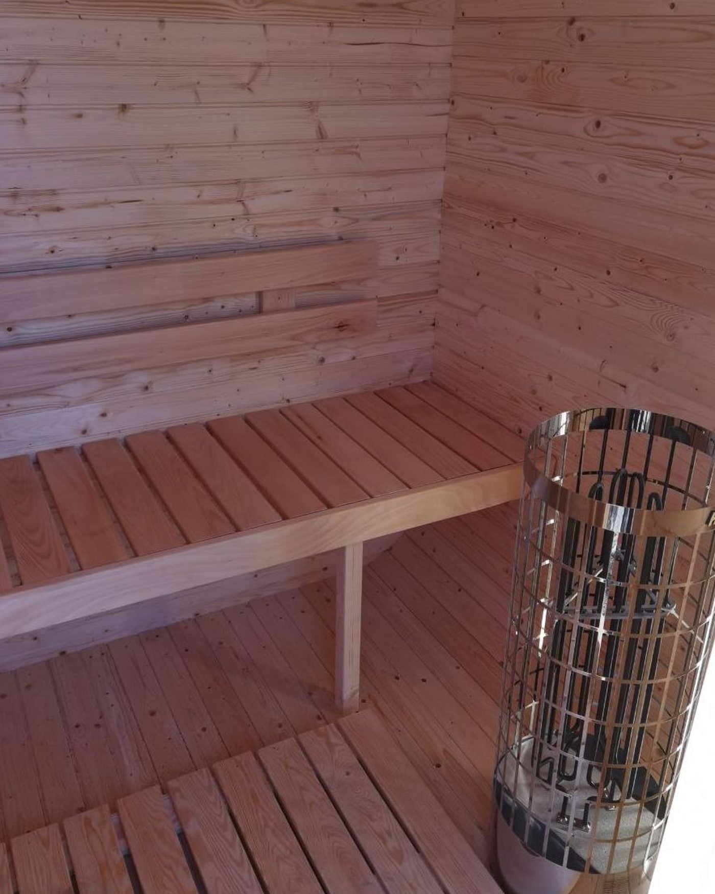 Harvia electric pillar heater with stones beside the bench inside The Cabin Three sauna