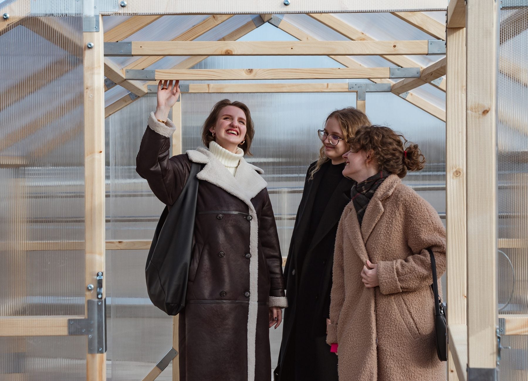 Three adults standing inside a NORDIC wooden greenhouse, showing the walk-in headroom