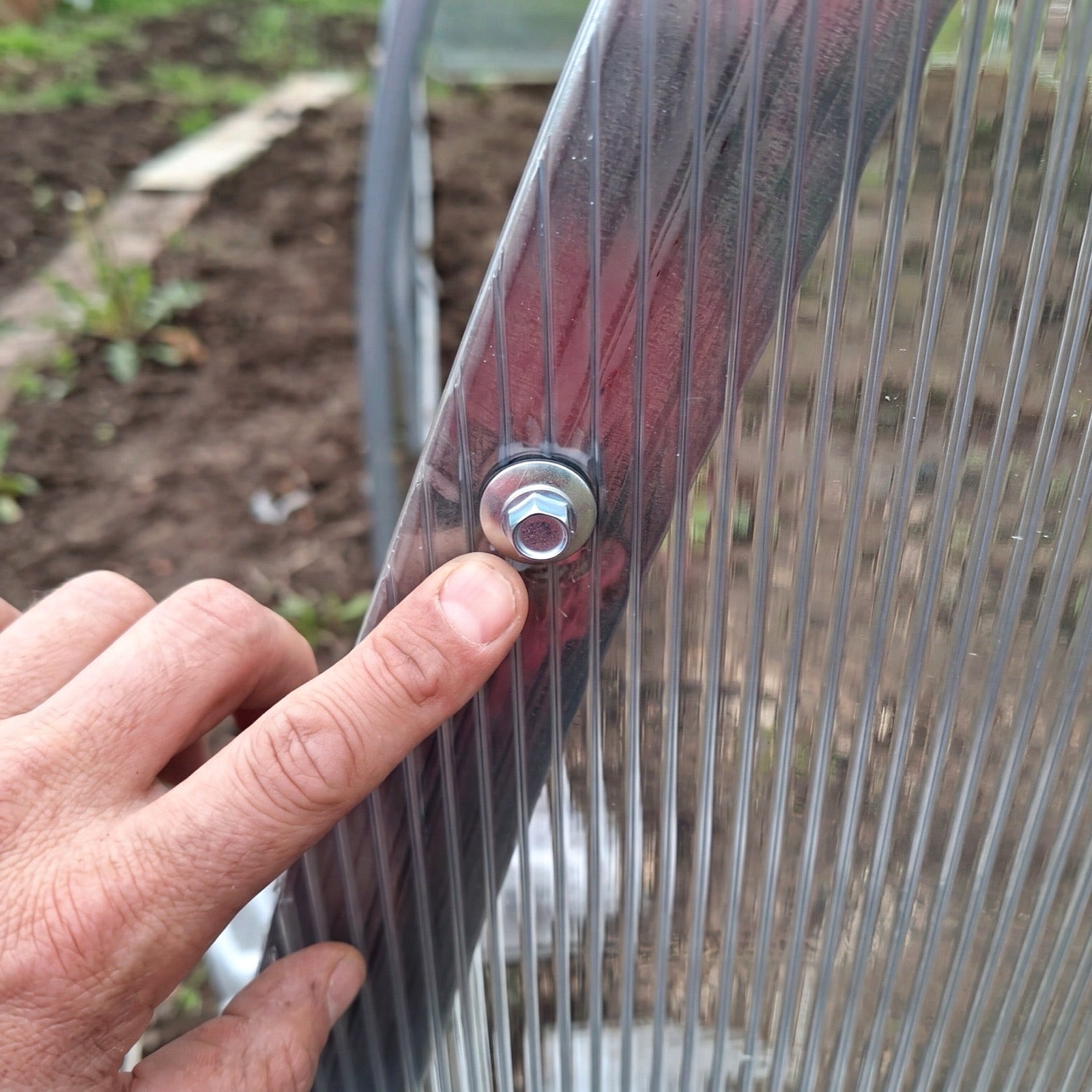 Twin-wall polycarbonate sheet fixed with a screw and washer on a SteelRoot greenhouse arch
