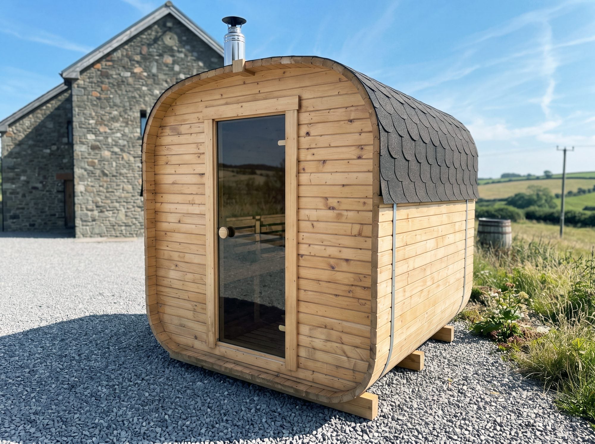 Wood-fired Cabin Three outdoor sauna with its flue, standing beside a stone house