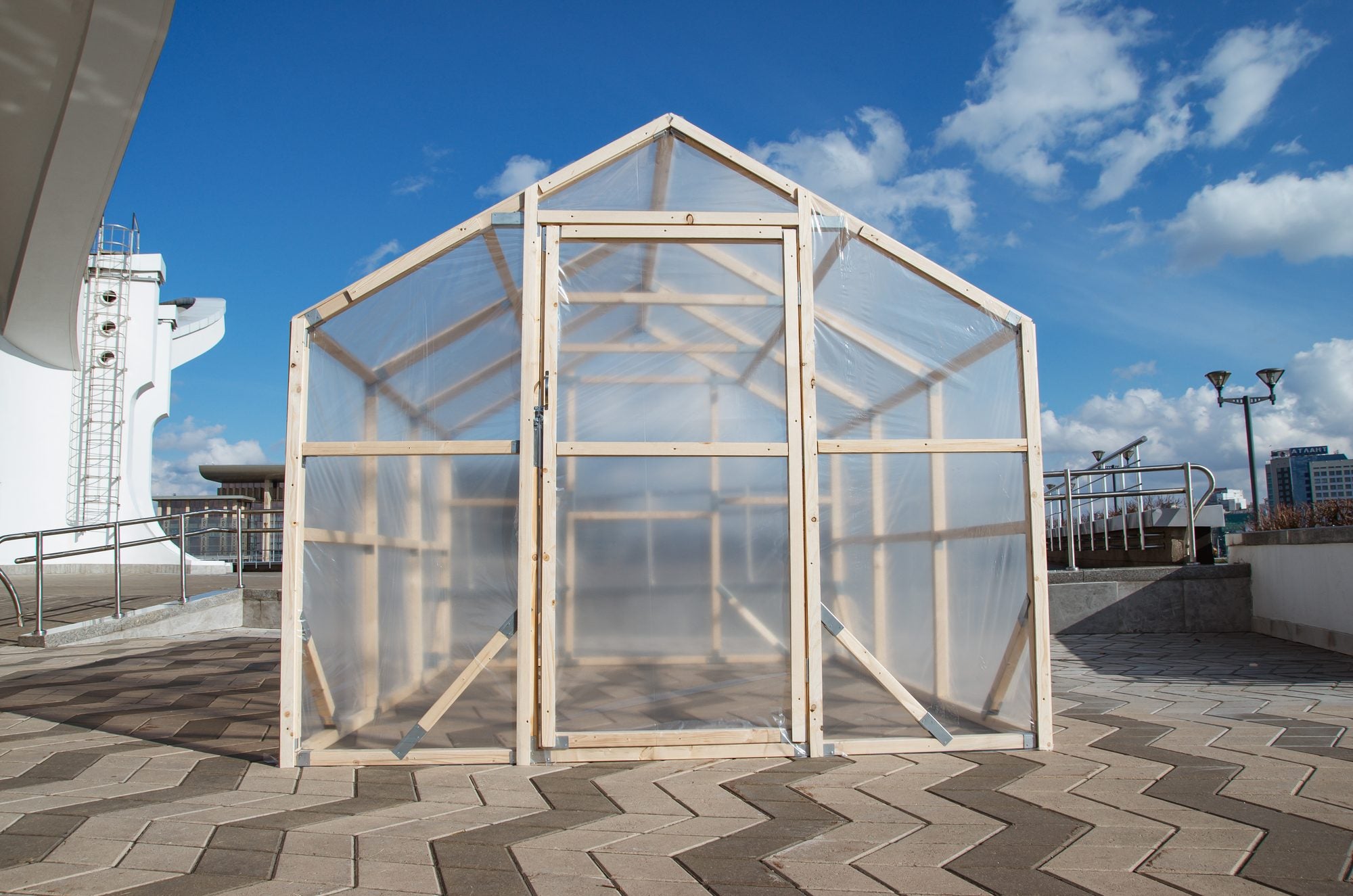 Gable end of a NORDIC wooden greenhouse with the door, pine frame and polycarbonate panels