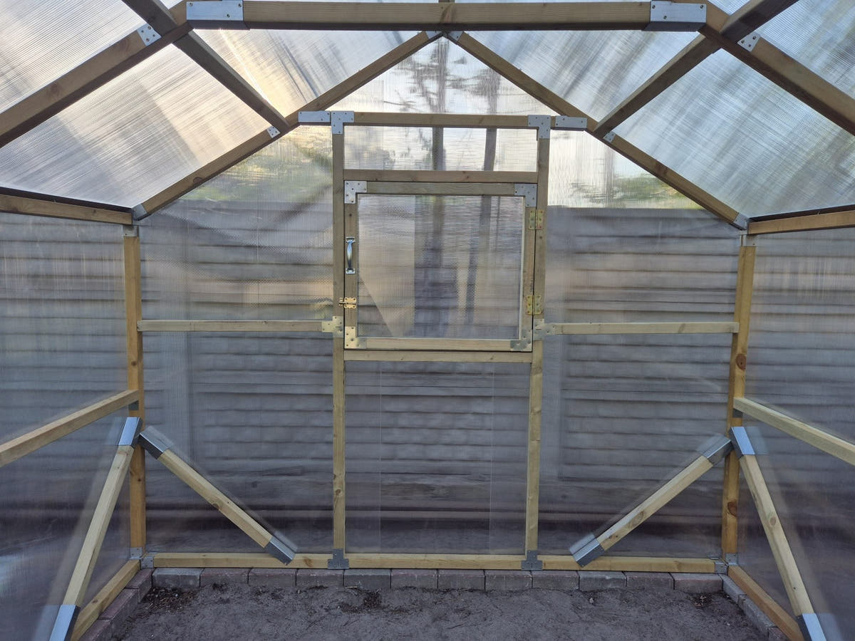 Gable end of a NORDIC greenhouse from inside, with the opening window above the braces