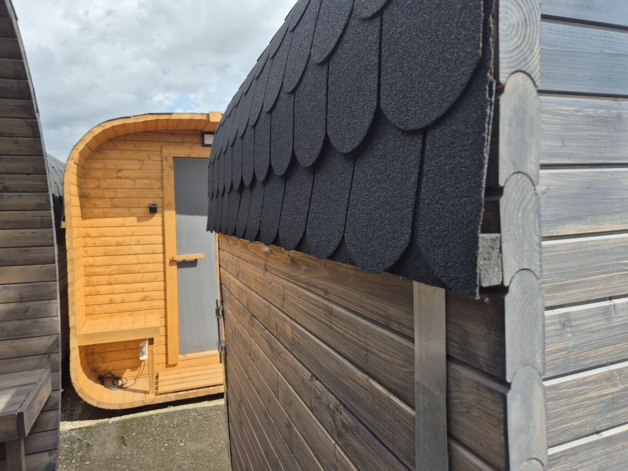 Outdoor saunas with shingle roofs fitted, waiting in the yard before dispatch