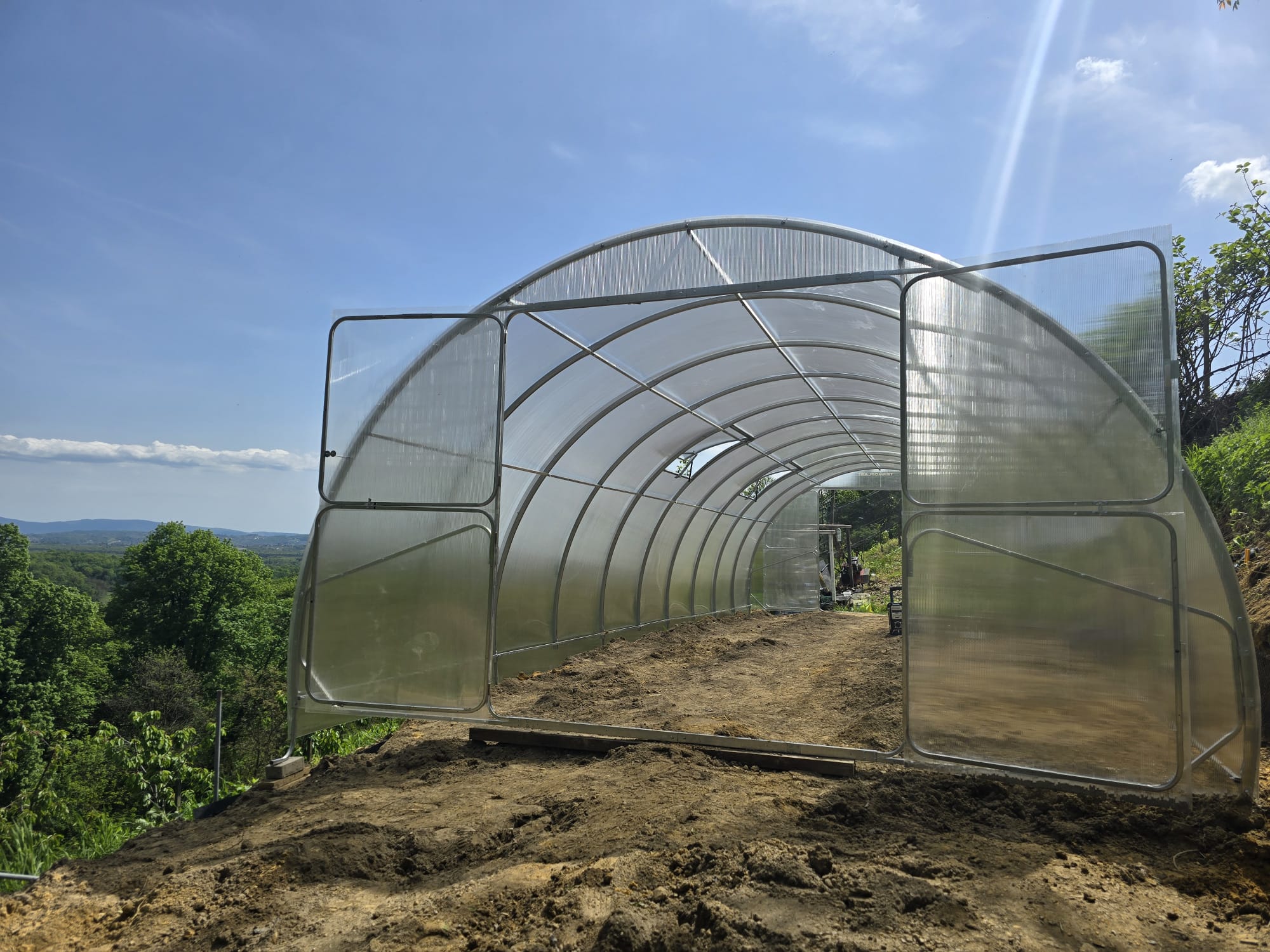 Galvanised steel arches of a SteelRoot Grand 4.00 greenhouse, seen through the open end