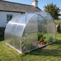 SteelRoot Plot 3.14 beside a whitewashed cottage, door open, vegetables growing inside