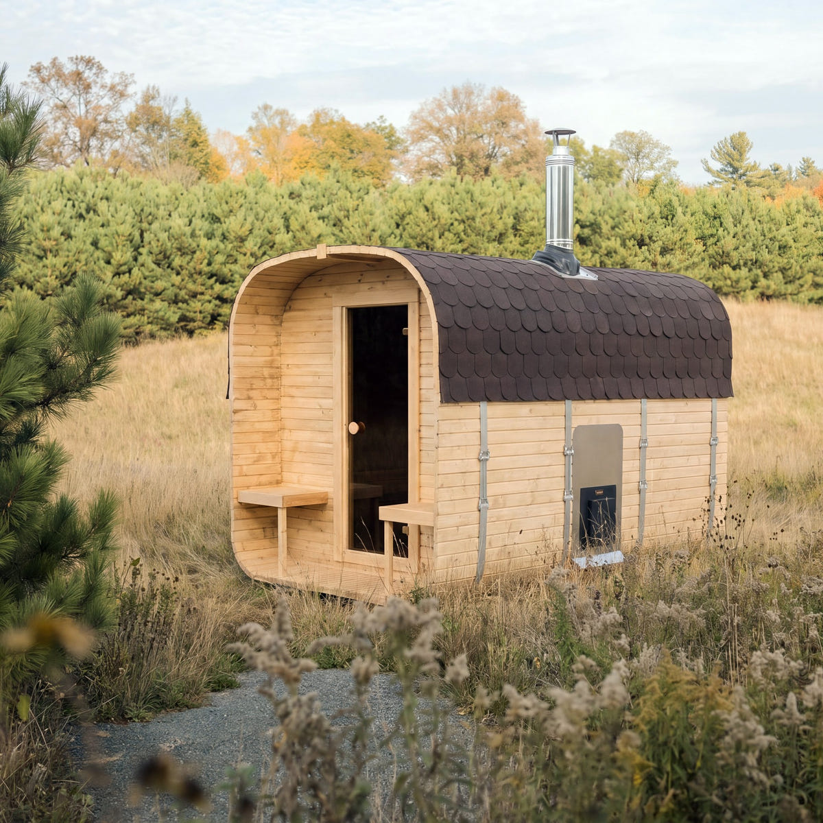 The Cabin Six Two-Tier wood-fired sauna in a meadow, the flue on the roof and the fire door on the long wall