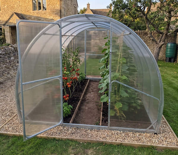 SteelRoot Plot 3.14 greenhouse with the door open in a stone cottage garden