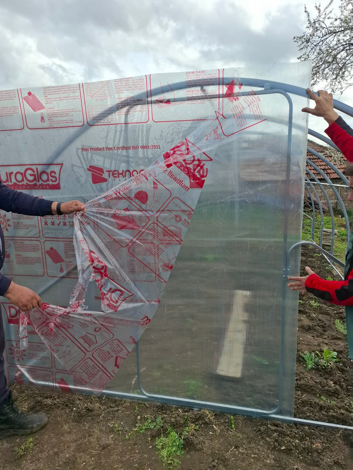 Two people peeling the protective film from an end wall panel of a Plot 3.14