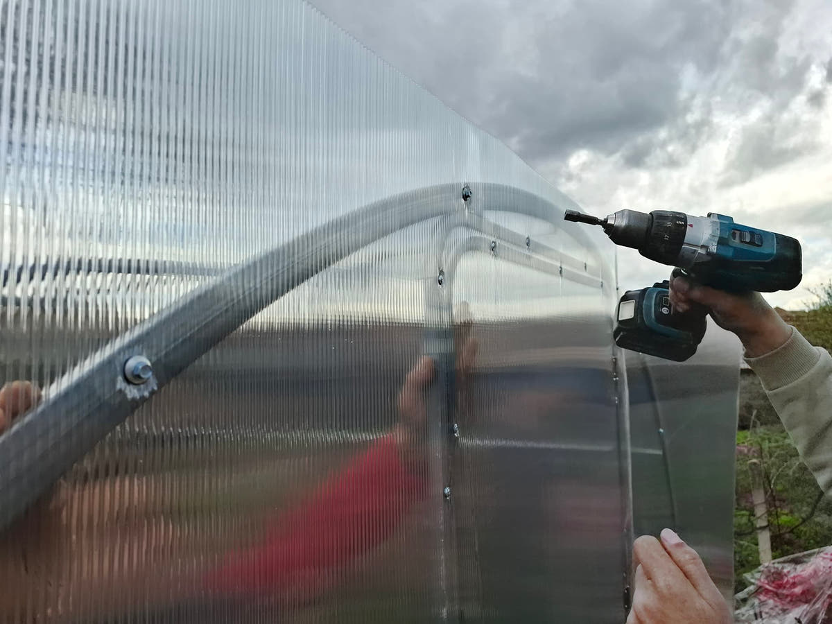 Self-drilling roofing screws fixing polycarbonate to the galvanised arch of a Plot 3.14